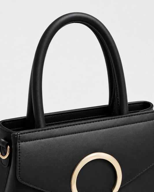 Close-up of black PORT&LOTUS structured tote bag with padded handles reinforced top edge and gold-tone side ring