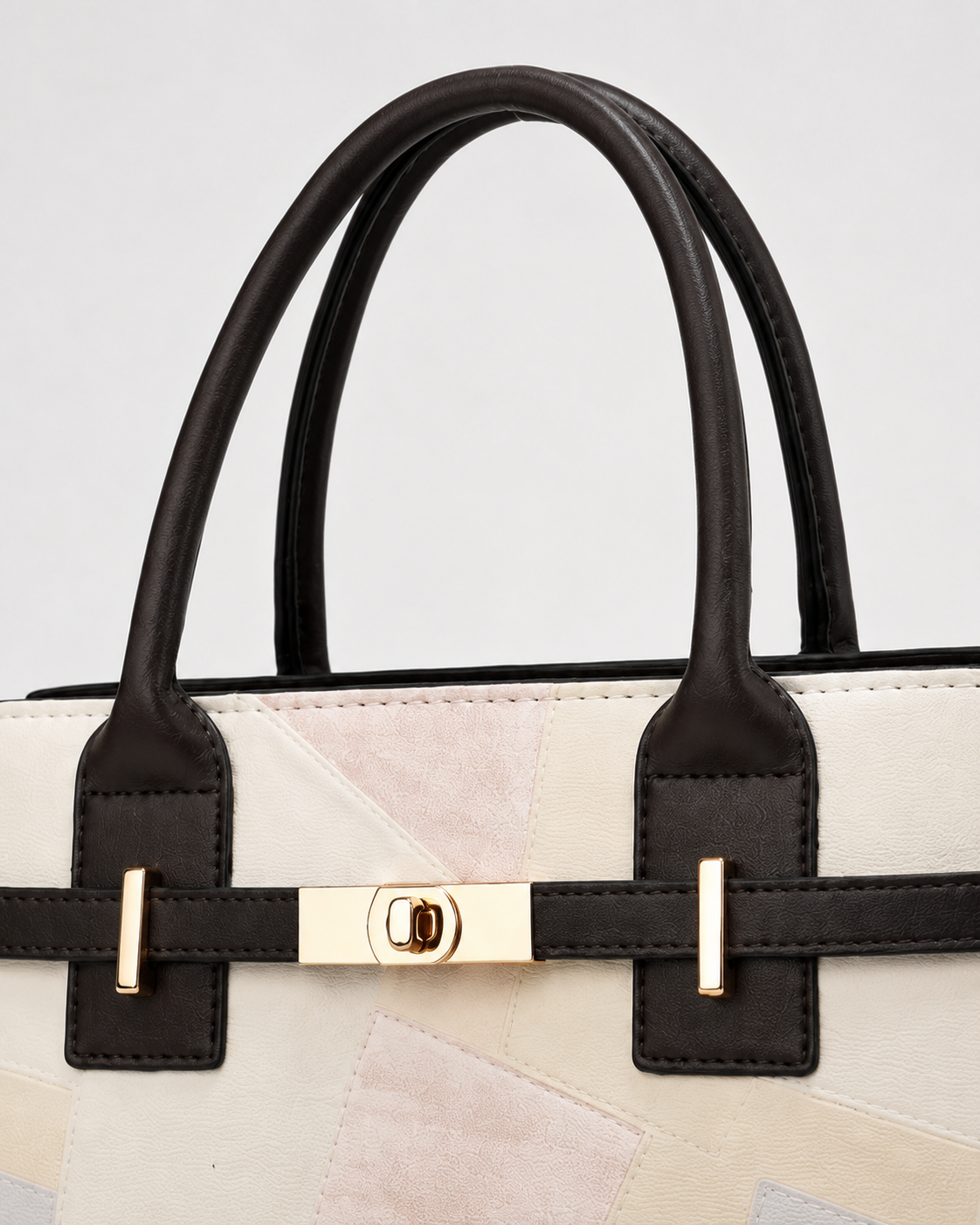 Close-up of ivory patchwork tote bag with dark brown top handles and polished gold-tone front turn-lock hardware