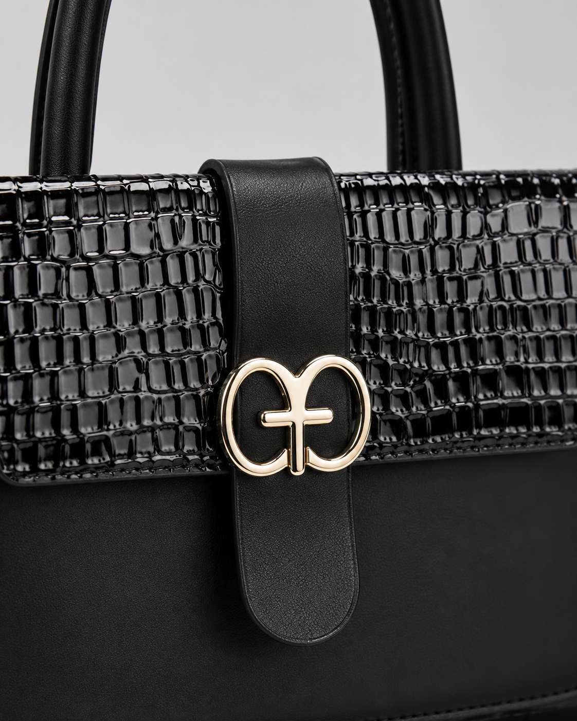 Close-up of black PORT&LOTUS handbag with black and pink crocodile embossed flap smooth vegan leather center strap and gold-tone clasp