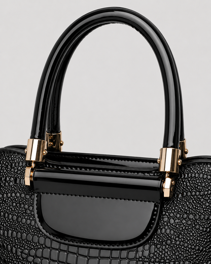 Close-up of black PORT&LOTUS handbag with glossy top handles crocodile texture and polished gold-tone fittings