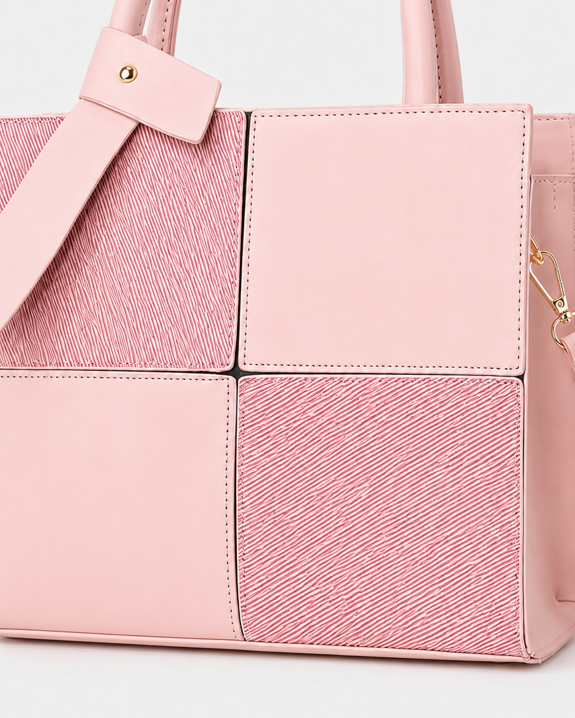 Close-up of pink structured tote bag showing smooth and textured square panels with detachable shoulder strap hardware