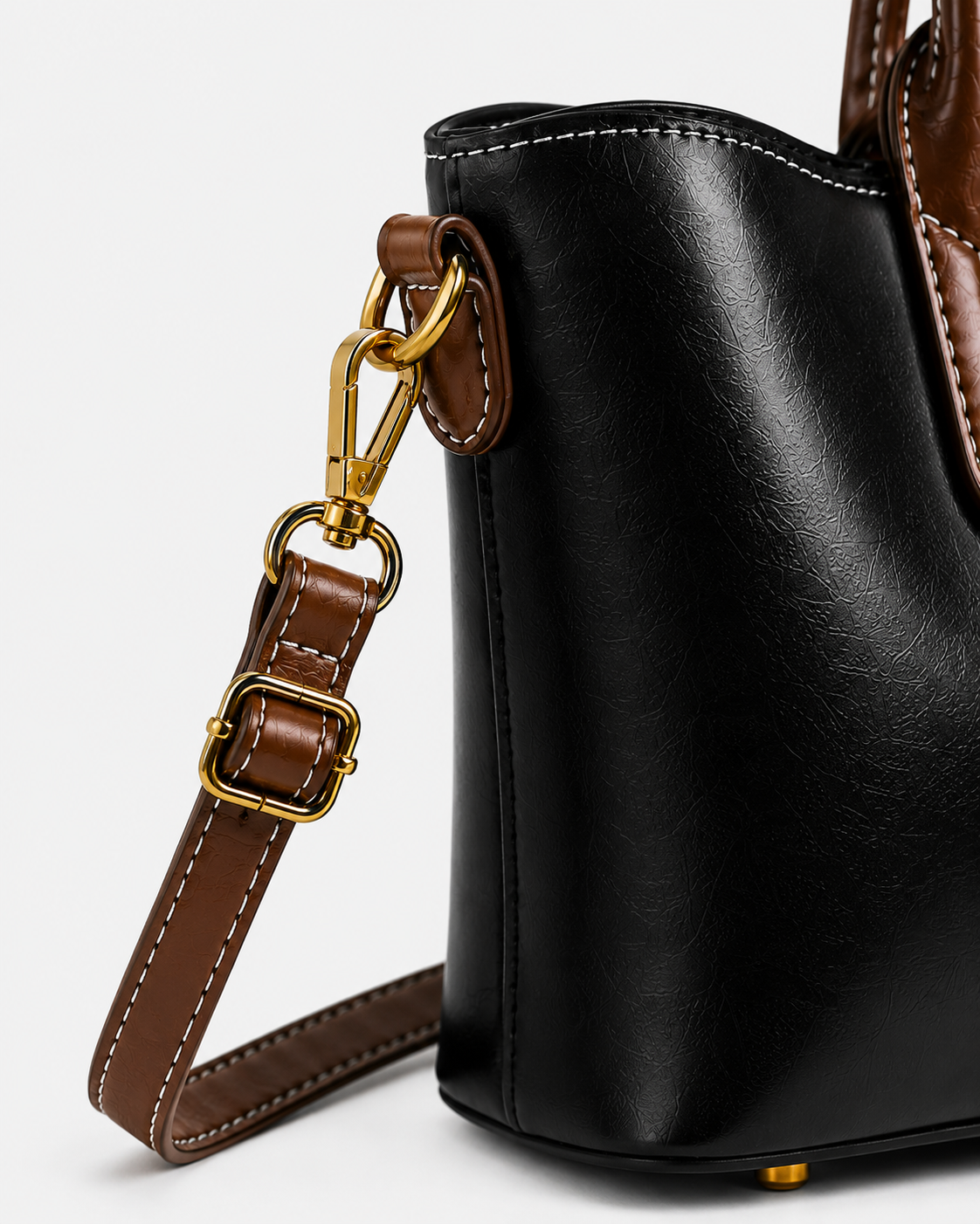Close-up of PORT&LOTUS black tote bag with detachable brown shoulder strap adjustable buckle swivel clasp and gold-tone hardware