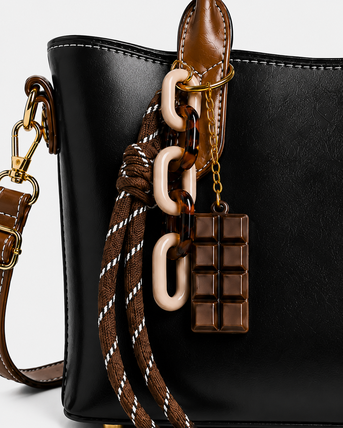 Close-up of PORT&LOTUS black tote handbag with decorative resin chain striped rope chocolate pendant charm and gold-tone hardware