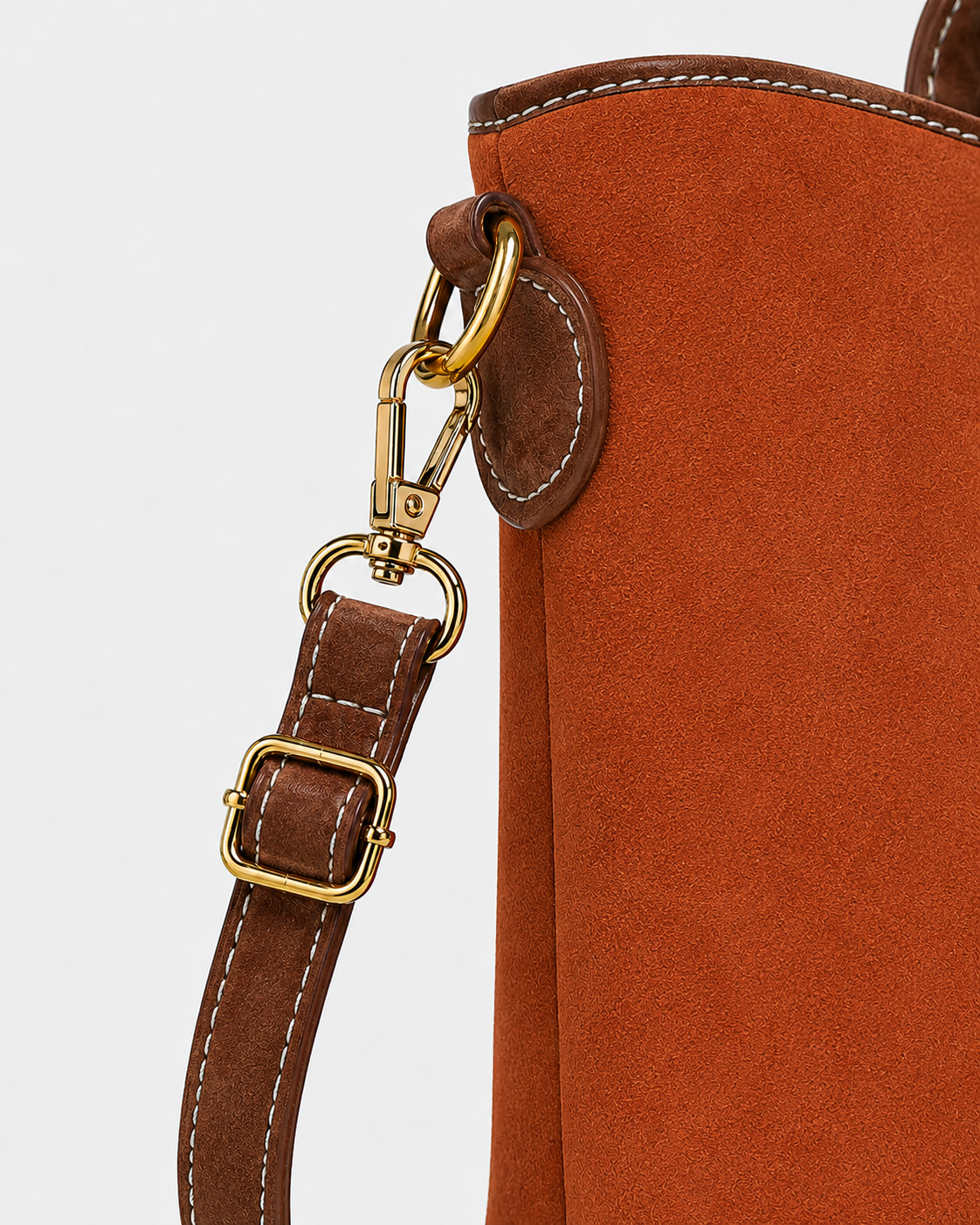 Close-up of PORT&LOTUS orange tote bag with detachable brown shoulder strap adjustable buckle swivel clasp and gold-tone hardware