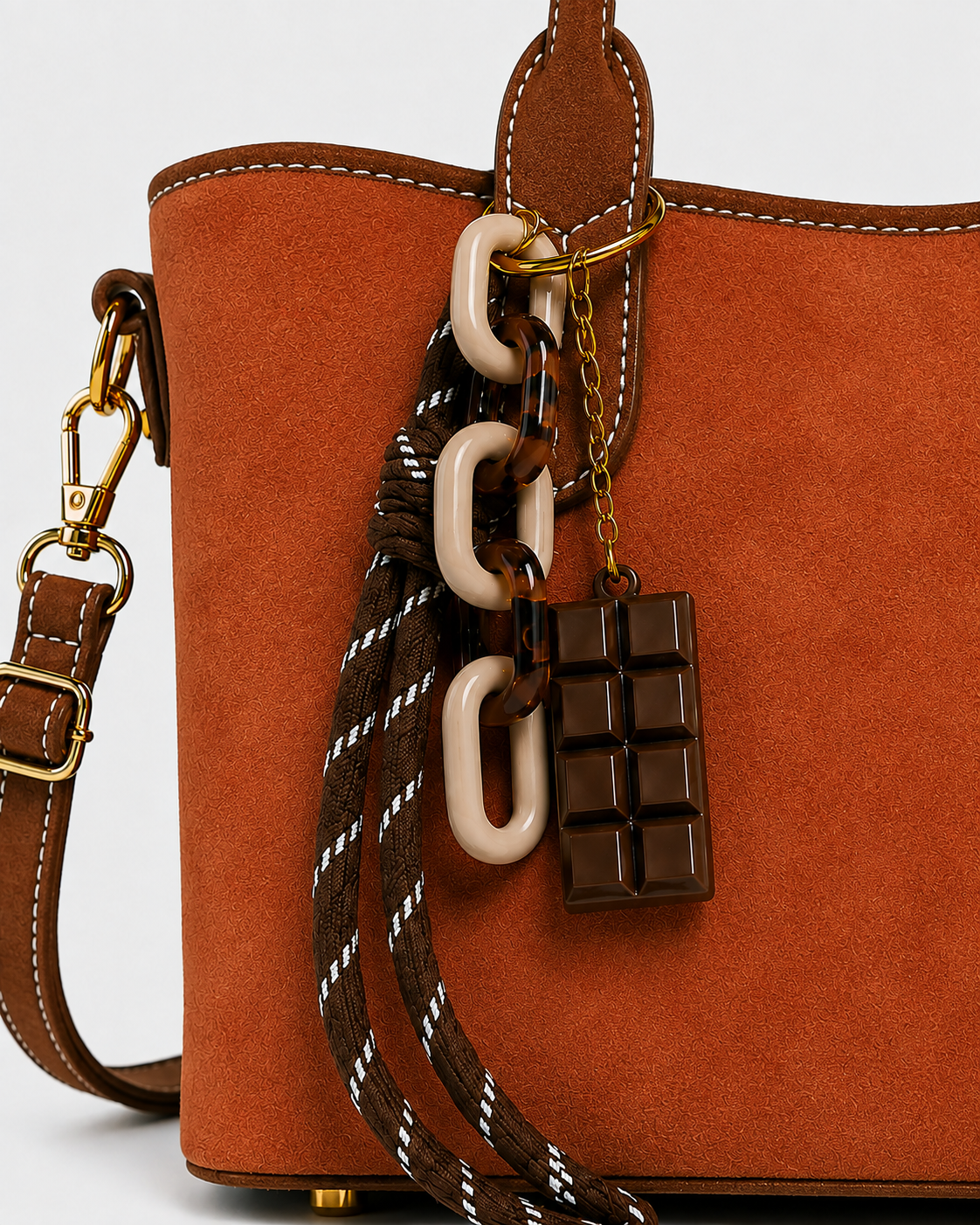 Close-up of PORT&LOTUS orange tote handbag with resin chain charm striped rope accent chocolate pendant and gold-tone hardware